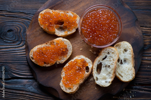 Sandwiches with salmon red caviar on a rustic wooden surface