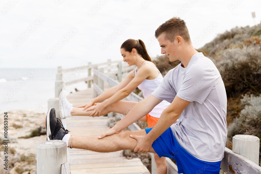 Runners. Young couple exercising and stertching on beach Runners. Young couple exercising and stertching on beach