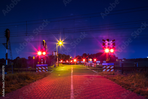 Bewaakte spoorwegovergang met brandende lichten in de nacht  photo