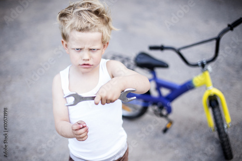 Funny toddler boy repairing his broken bike. Childhood.Cycling