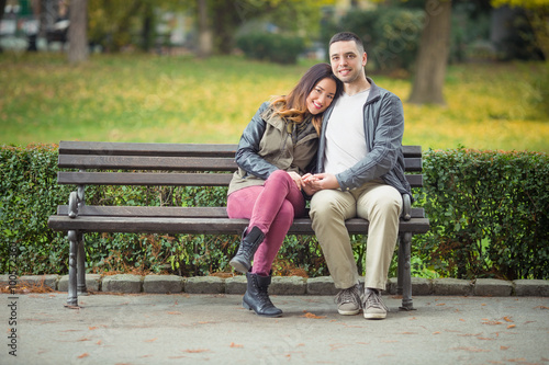 Romantic young couple sitting on a bench in a park