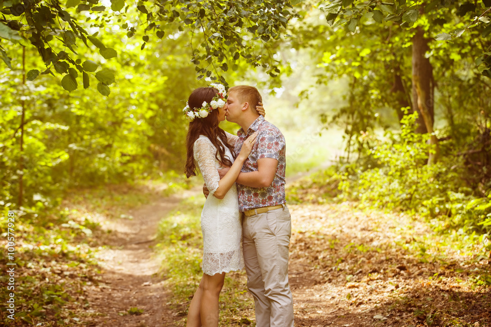 Beautiful girl with flowers circlet is kissing young boyfriend