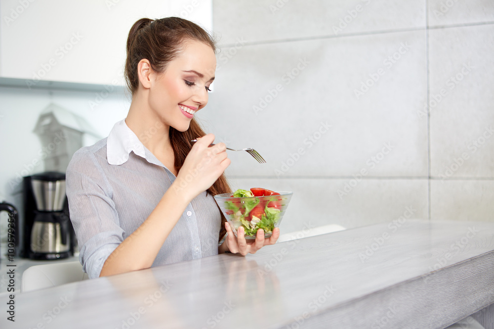 Casual brunette posing while eating salad and holding a mixed sa Casual brunette posing while eating salad and holding a mixed sa