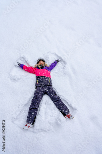 Top view of cute girl lying on snow