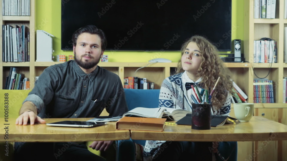 couple of students sitting in the class room and watching to the camera couple of students sitting in the class room and watching to the camera