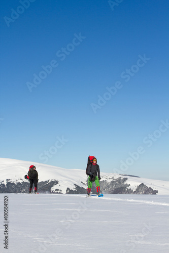 Winter hiking in the mountains on snowshoes with a backpack and tent.