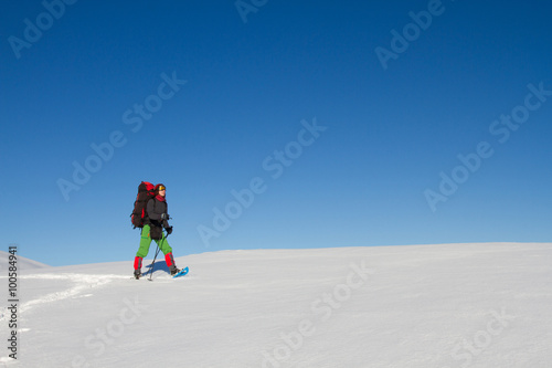 Winter hiking in the mountains on snowshoes with a backpack and tent.