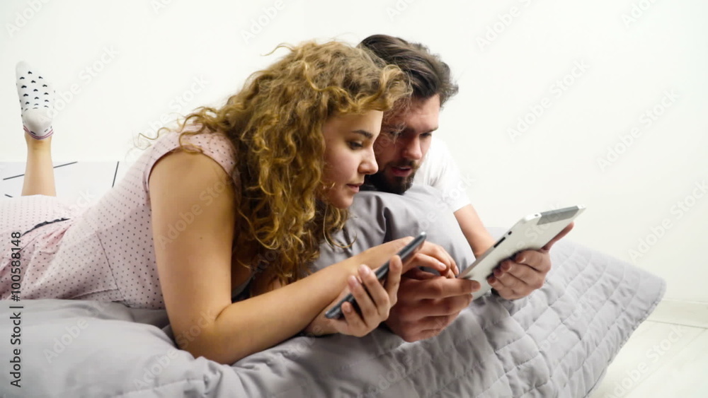 man and woman using their gadgets in bed slow motion man and woman using their gadgets in bed slow motion