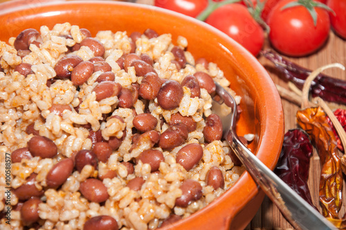 Cazuela de arroz con alubias y varios ingredientes sobre un mantel de rafia