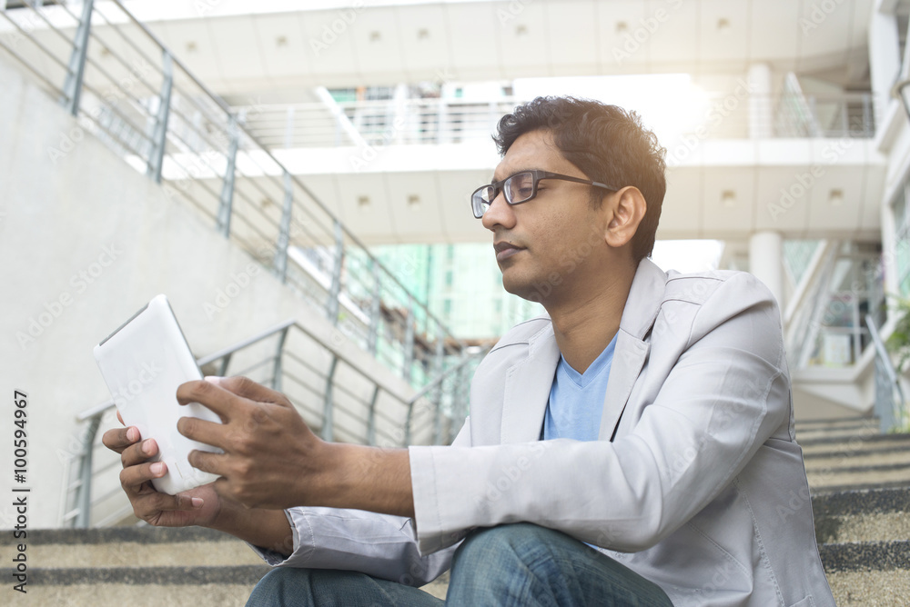 indian male using tablet outdoor