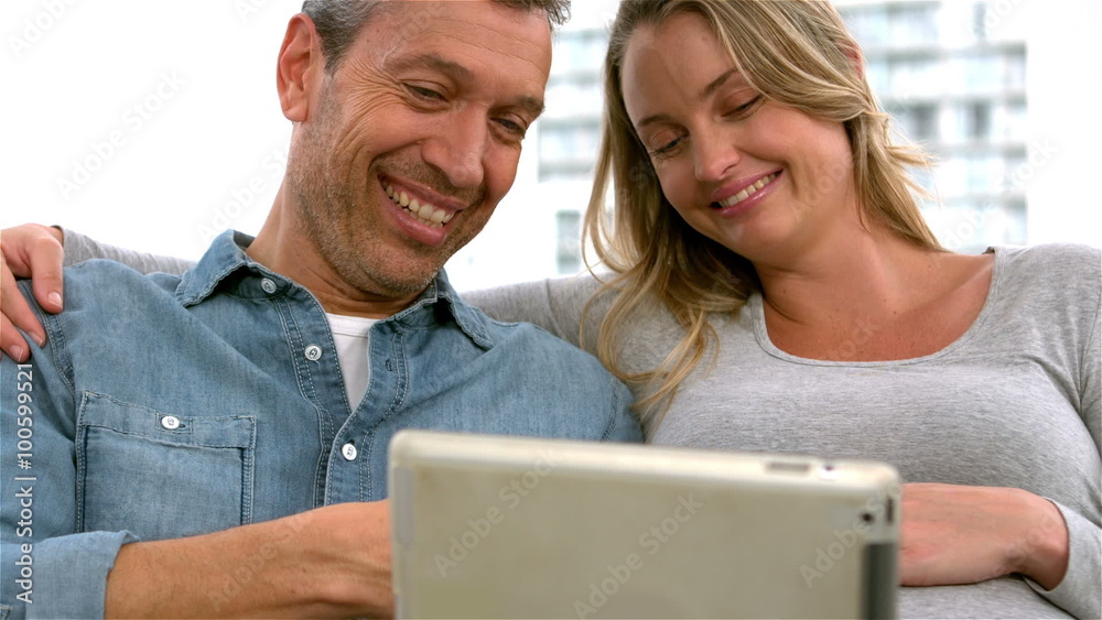 Smiling future parents using tablet Smiling future parents using tablet