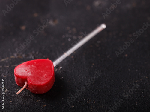 Red candle in the shape of a heart on a dark background.The background to the romantic holiday of Valentine's day.Copy space.selective focus.