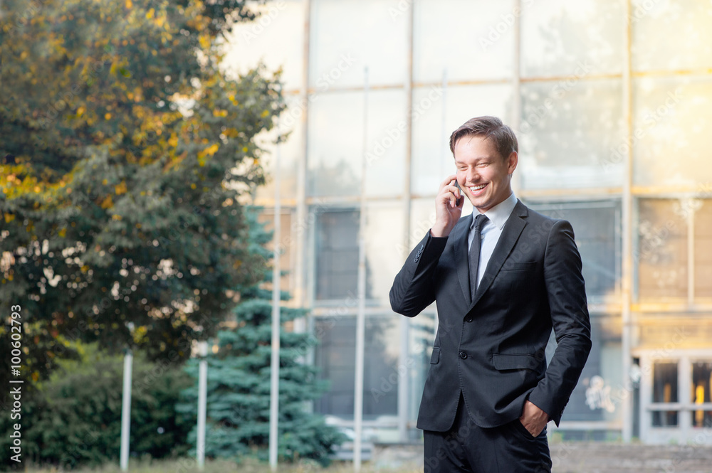 Happy young businessman talking on the mobile phone