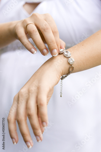 Руки девушки/невесты с обручальным кольцом и серебряным браслетом с крупными прозрачными камнями 