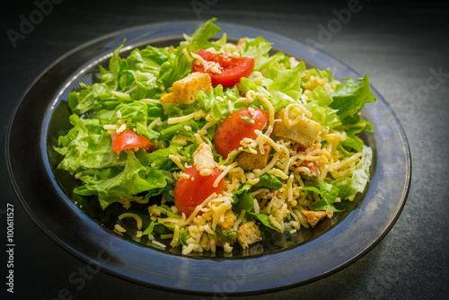 Caesar salad made of fresh vegetables on dark background. Selective focus.