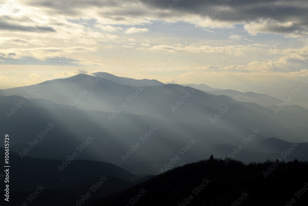 mountain silhouettes with sunbeams at sunset