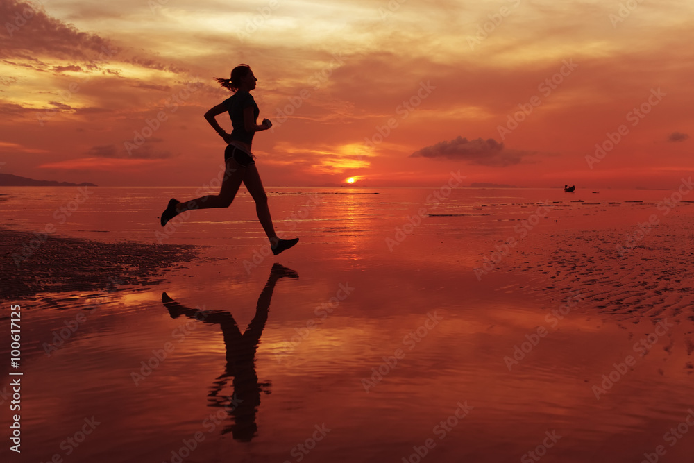  Runner jogger on sunrise  ru  along the sand beach with mirror on the water