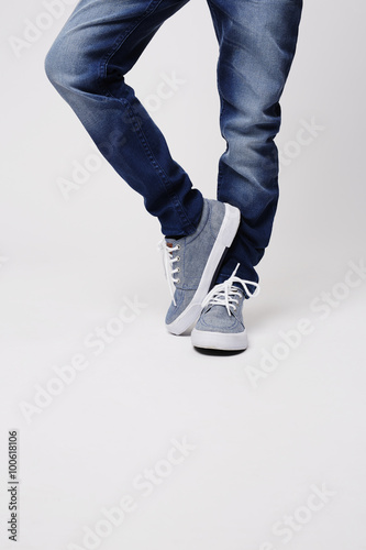 Young boy in jeans and sneakers, low section