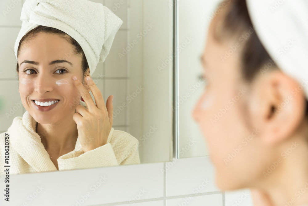 Woman applying moisturizer to her face Woman applying moisturizer to her face