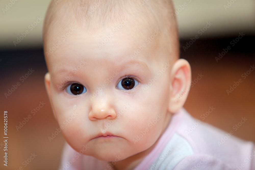 Close-up of a small child who cries but does not scream. A tear rolling down his cheek. Blurred background. Photo girl.
