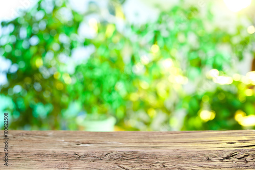Wooden desk and blurred foliage on the background.