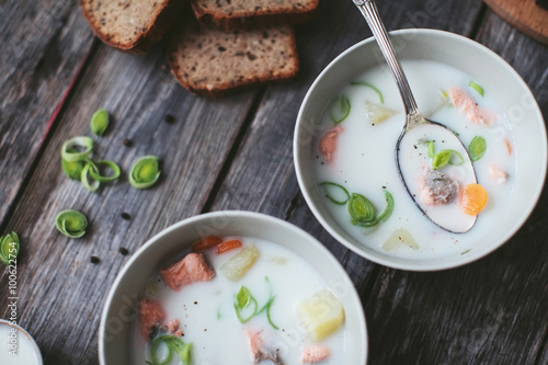 Finnish dairy ear with red fish in a plate with a spoon on a wooden table with bread, herbs and fish photo