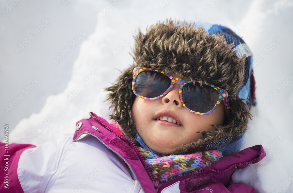Portrait of a little girl in the snow with winter clothes and sunglasses Portrait of a little girl in the snow with winter clothes and sunglasses