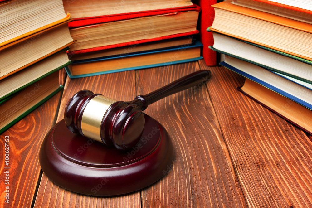 Law book with wooden judges gavel on table in a courtroom or law enforcement office. Law book with wooden judges gavel on table in a courtroom or law enforcement office.