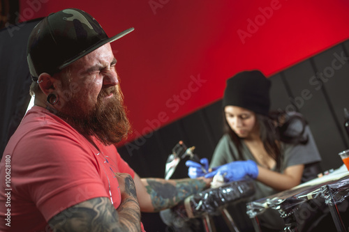 Beautiful brunette girl makes tattoo. Tattooist makes a tattoo. Closeup