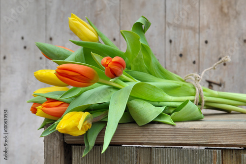 bouquet de tulipes jaunes et orange sur caisse en bois