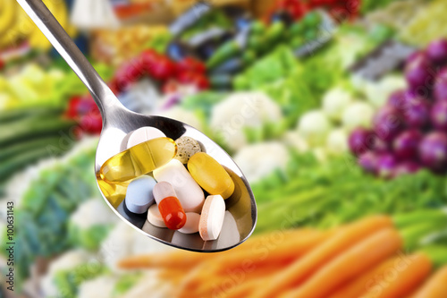 spoon with pills, dietary supplements on vegetables background