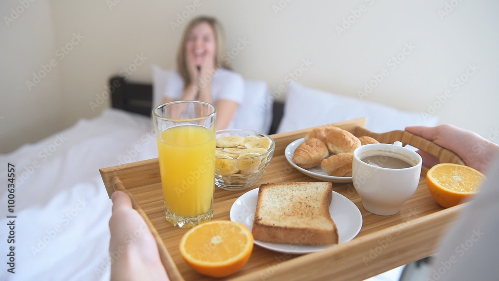 Hands holding breakfast tray for happy woman.