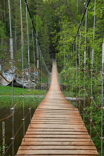 Wooden suspension bridge over the river in the forest