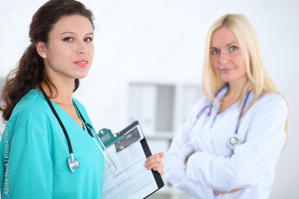 Two confident friendly female doctors sitting at the table and listen to the patient's history . Medical and health care concept Two confident friendly female doctors sitting at the table and listen to the patient's history . Medical and health care concept