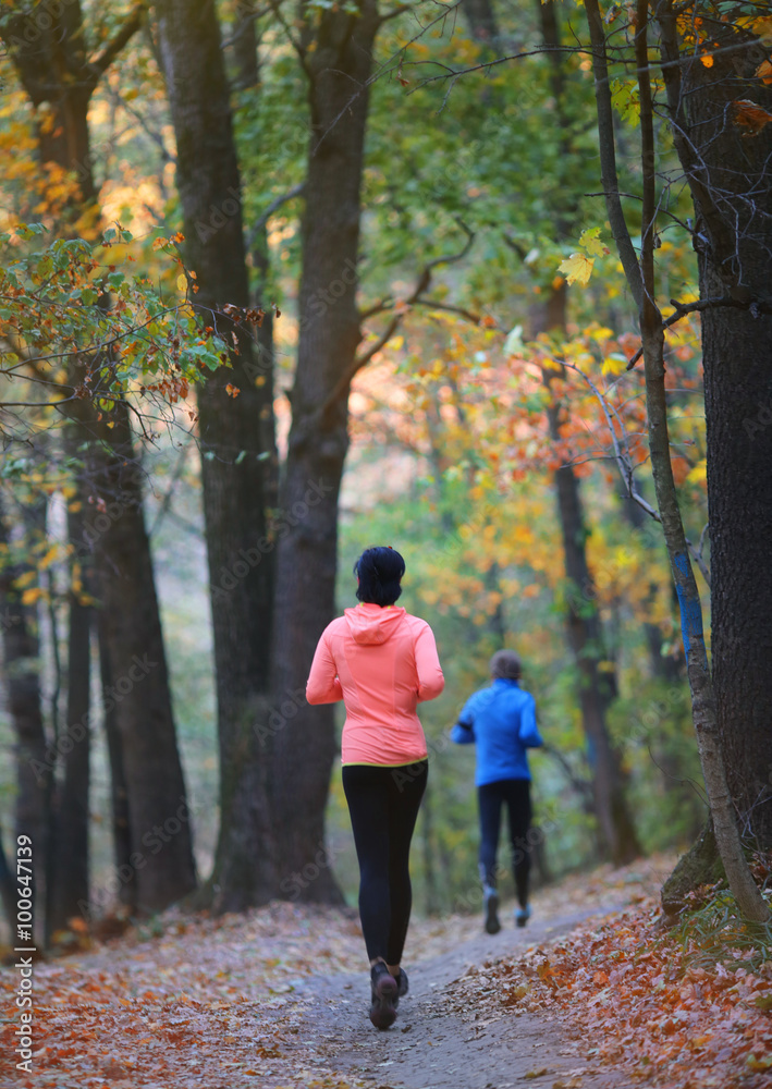 Athlete runners feet running on the autumn forest road Athlete runners feet running on the autumn forest road