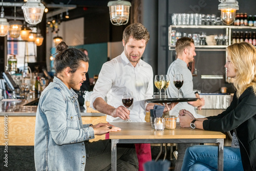 Waiter Serving Wine To Customers In Bar