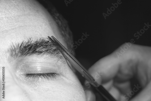 Portrait of man cutting eyebrow hairs. photo