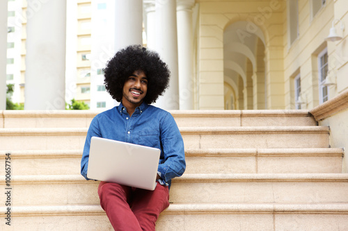 Cool black guy sitting outside using laptop