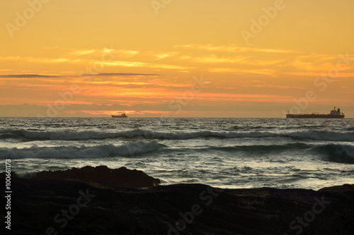 Ozean mit der Silhouette von 2 Schiffen zum Sonnenuntergang