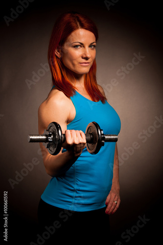 Beautiful young woman working out with dumbels in fitness gym