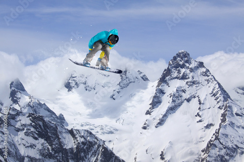 Flying snowboarder on mountains. Extreme sport.