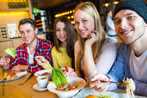 Group of girls and boys eat at the cafe.
