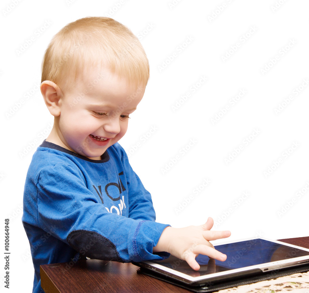 The little boy laughs and drives a finger on the tablet The little boy laughs and drives a finger on the tablet