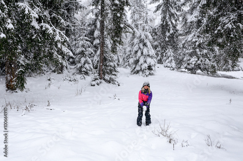 Girl play snowballs in winter snow-covered forest
