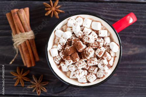 Cocoa with marshmallows in a red cup on a wooden table