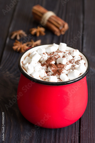 Cocoa with marshmallows in a red cup on a wooden table