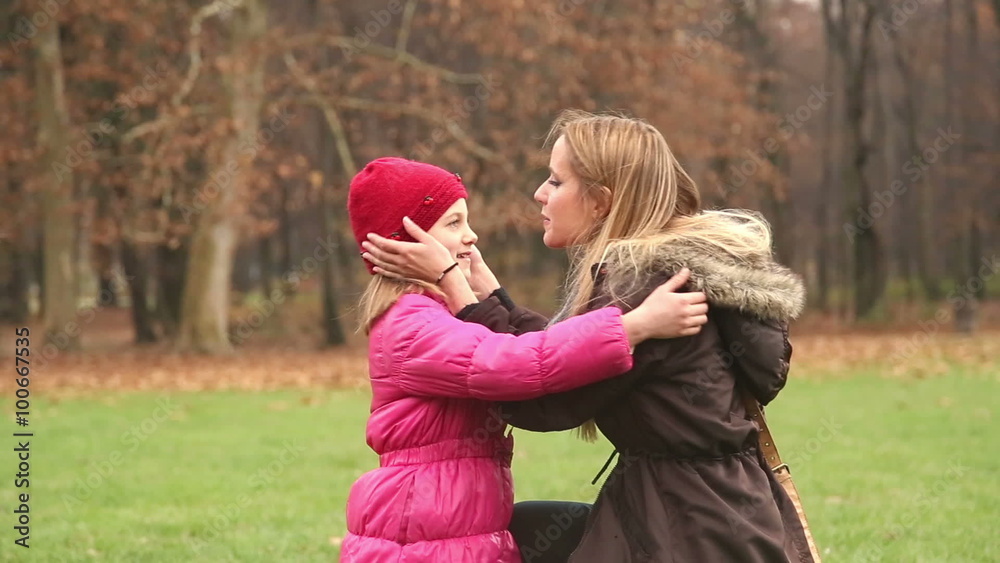 Mother putting cap on daughter's head and kissing her in forehead Mother putting cap on daughter's head and kissing her in forehead