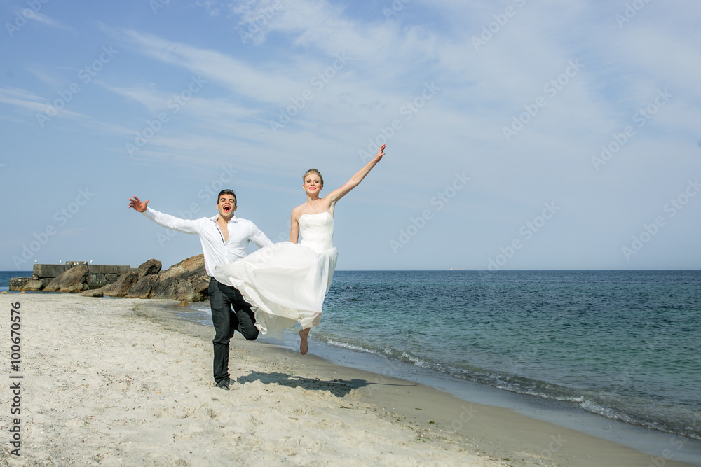 a young couple running at the beach, wedding at the sea, beautiful white wedding dress a young couple running at the beach, wedding at the sea, beautiful white wedding dress