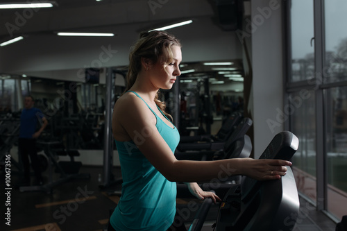 Pretty woman walking on treadmill in fitness center