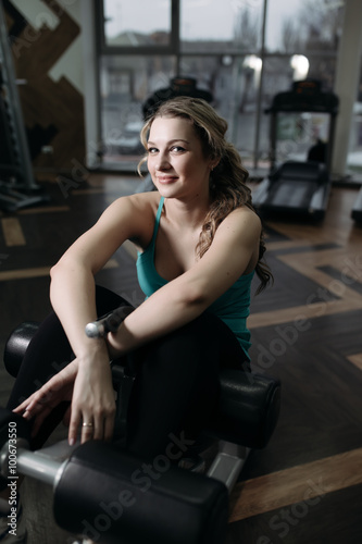 Beautiful woman sitting on a bench for press exercise in gym